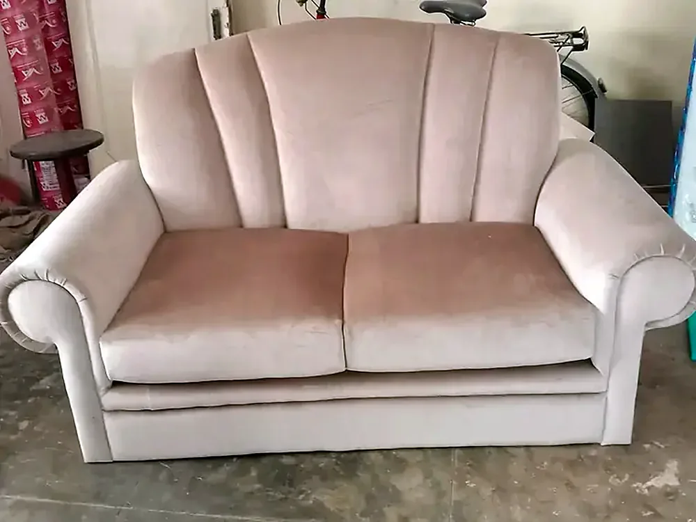 Blush two-seater with a scalloped back and rolled arms