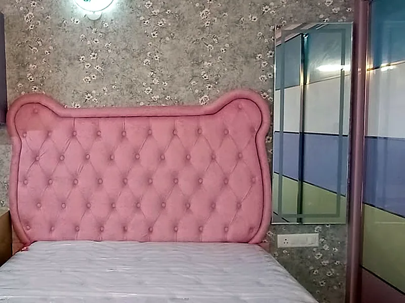 A rose diamond-tufted headboard fitted to a king bed